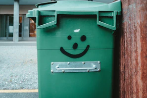 A team member standing next to a dumpster dino container filled with yard waste, smiling.
