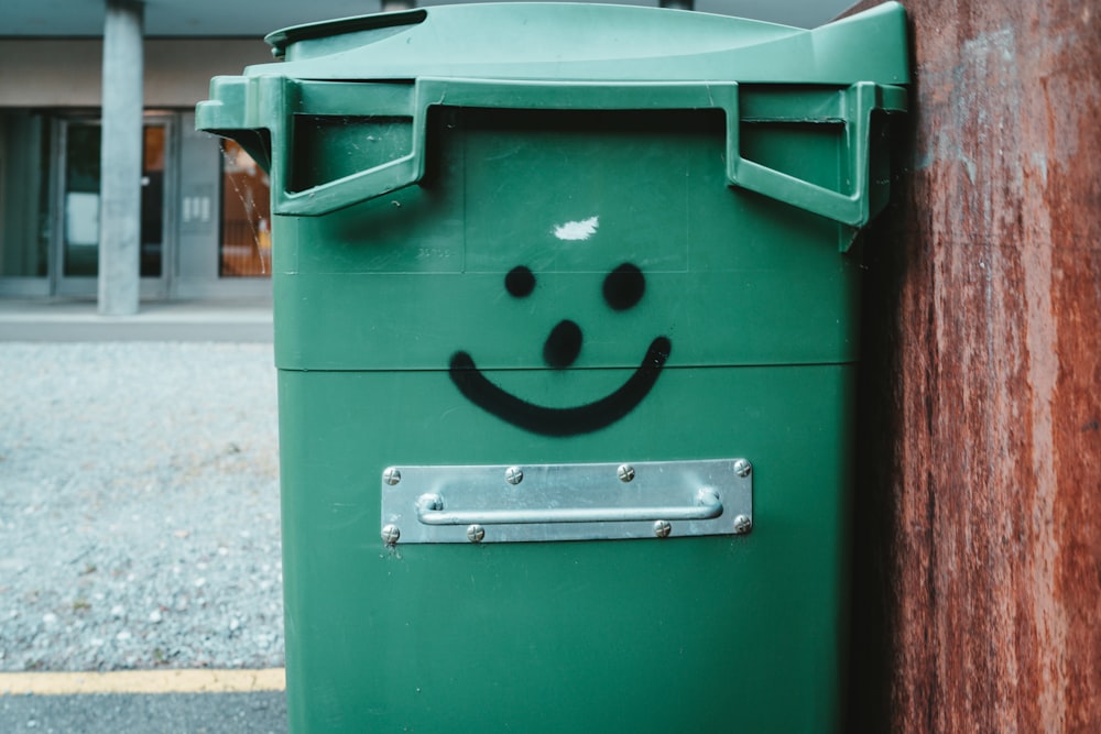 green trash bin on sidewalk