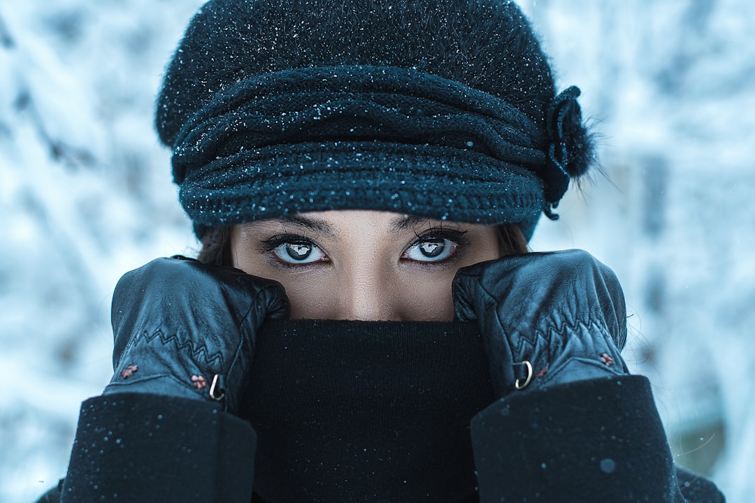 woman in black knit cap covering her face with her hand