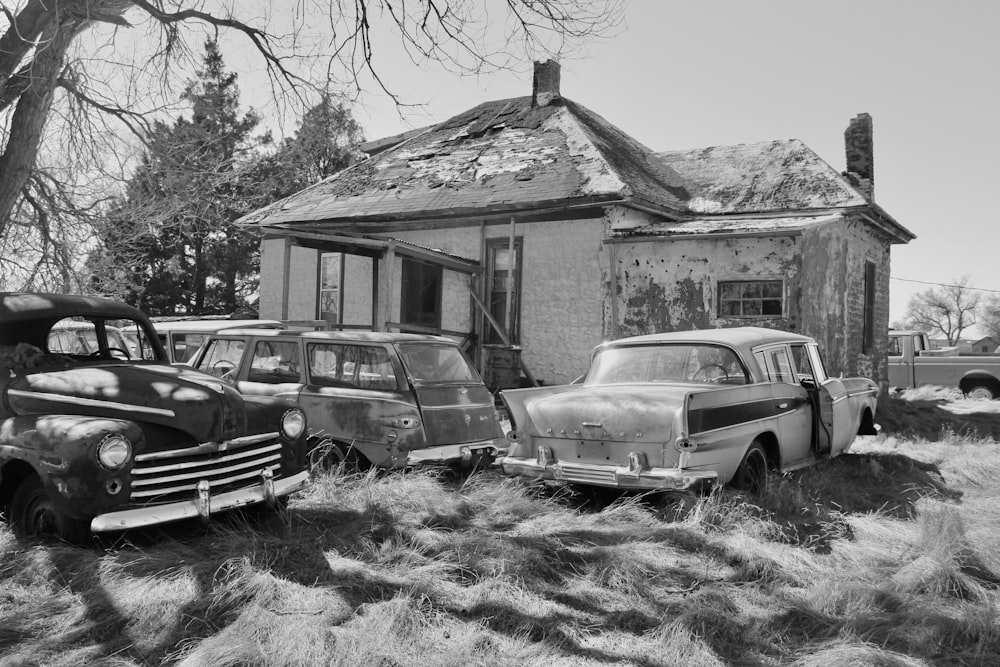 grayscale photo of 2 cars parked beside house