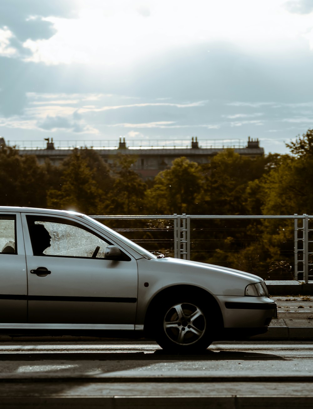 silver sedan parked beside gray metal fence during daytime