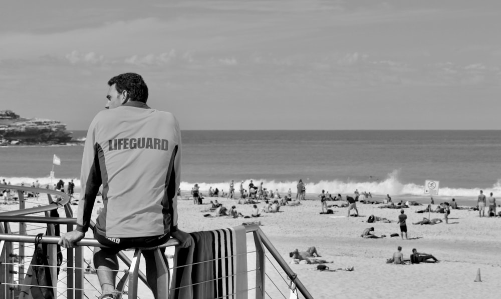 회색과 검은색 긴팔 셔츠를 입은 남자가 낮에 하얀 모래 해변에 서 있다