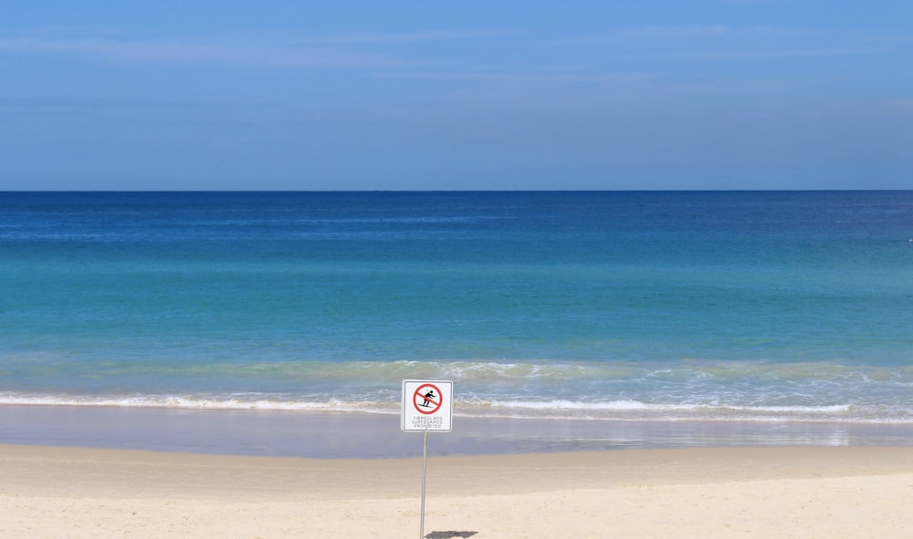 white and red no smoking sign on beach during daytime