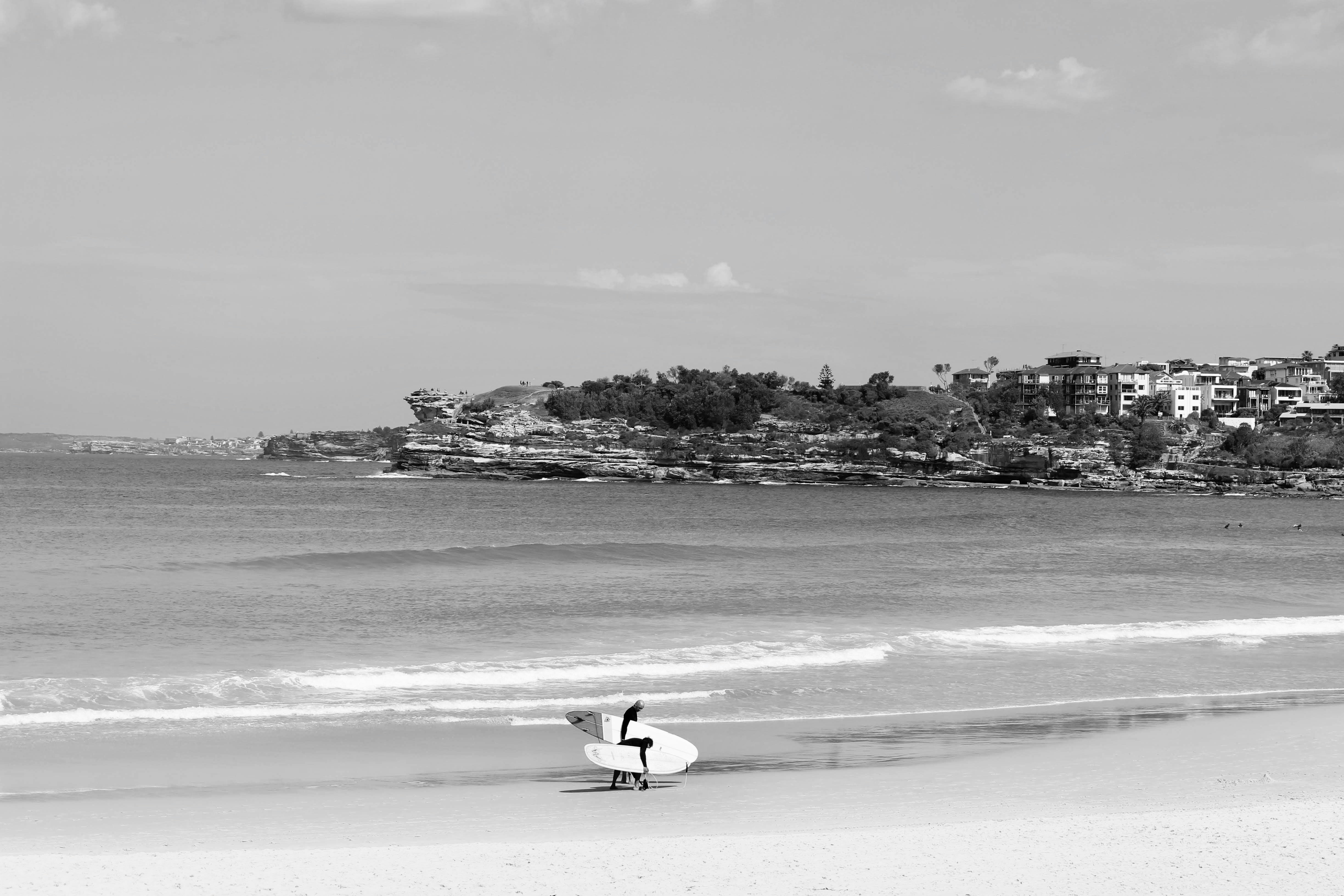 grayscale photo of man surfing on beach
