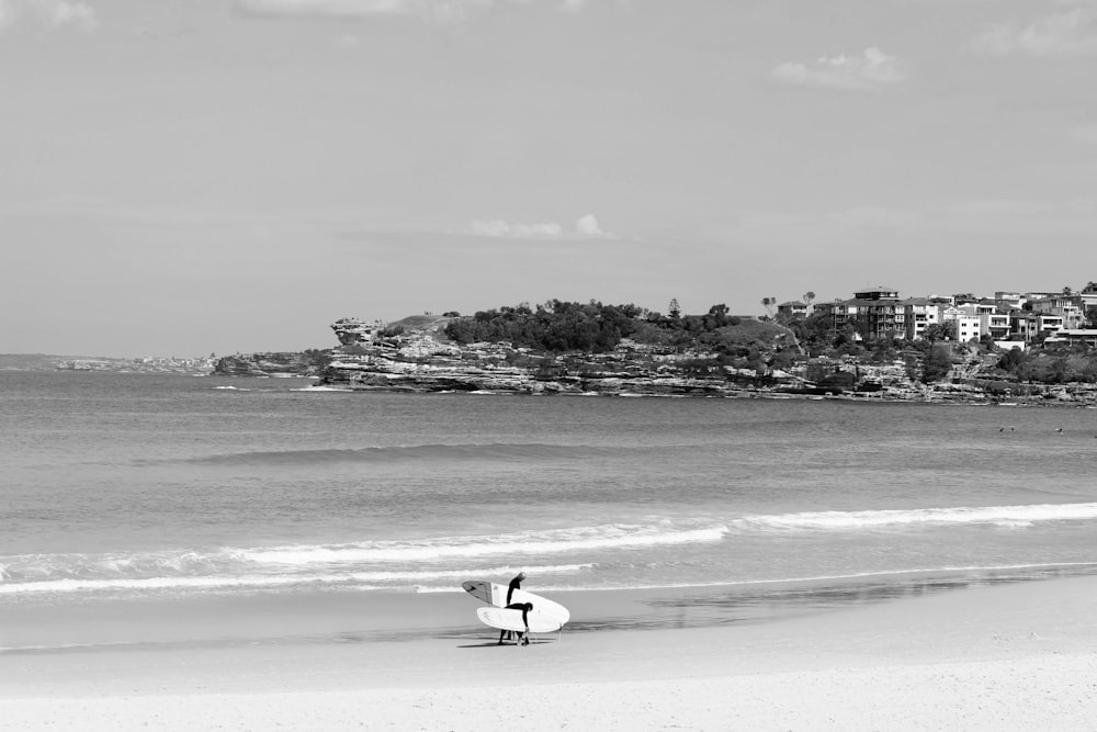 grayscale photo of man surfing on beach