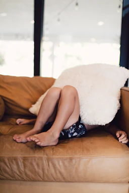 woman in black and white floral dress lying on brown couch