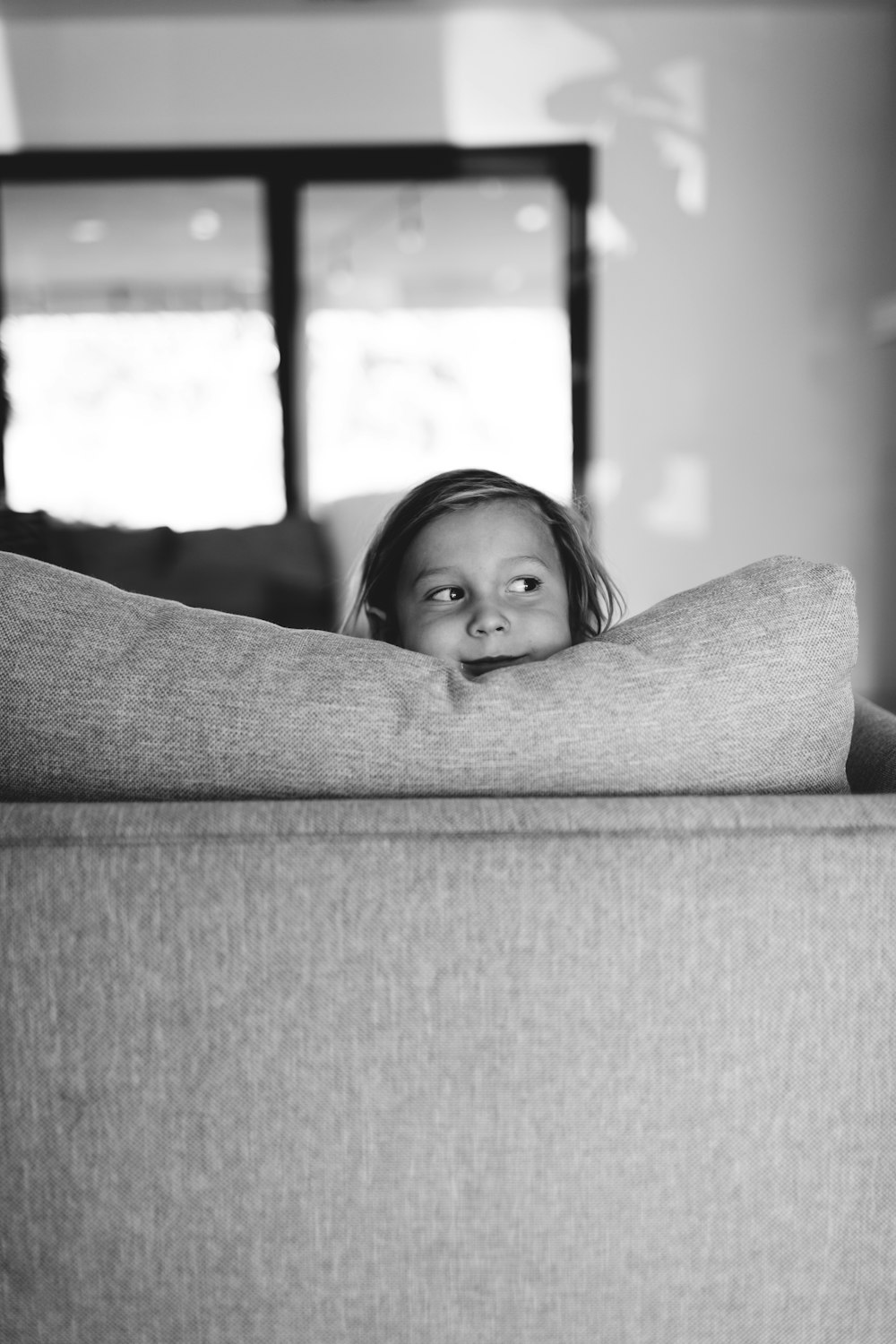 grayscale photo of child lying on sofa