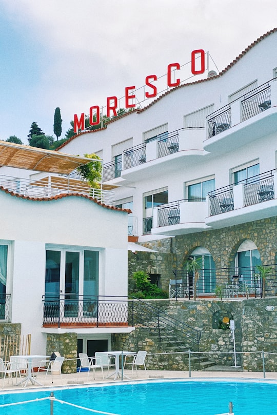 white concrete building with red and white signage in 18013 Diano Marina Italy