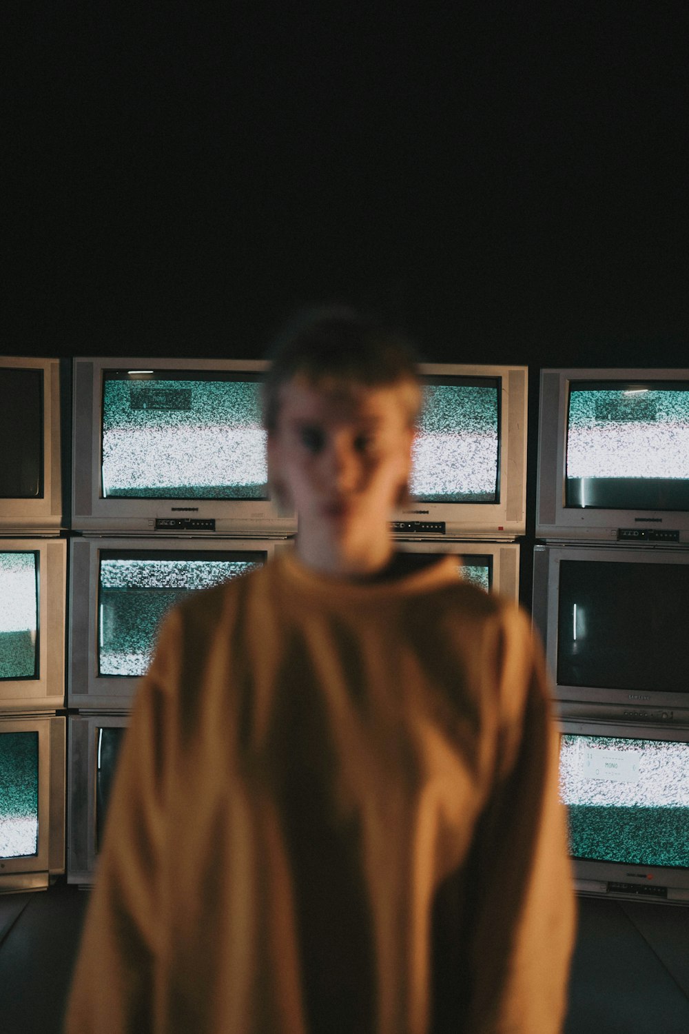 man in brown sweater standing near window