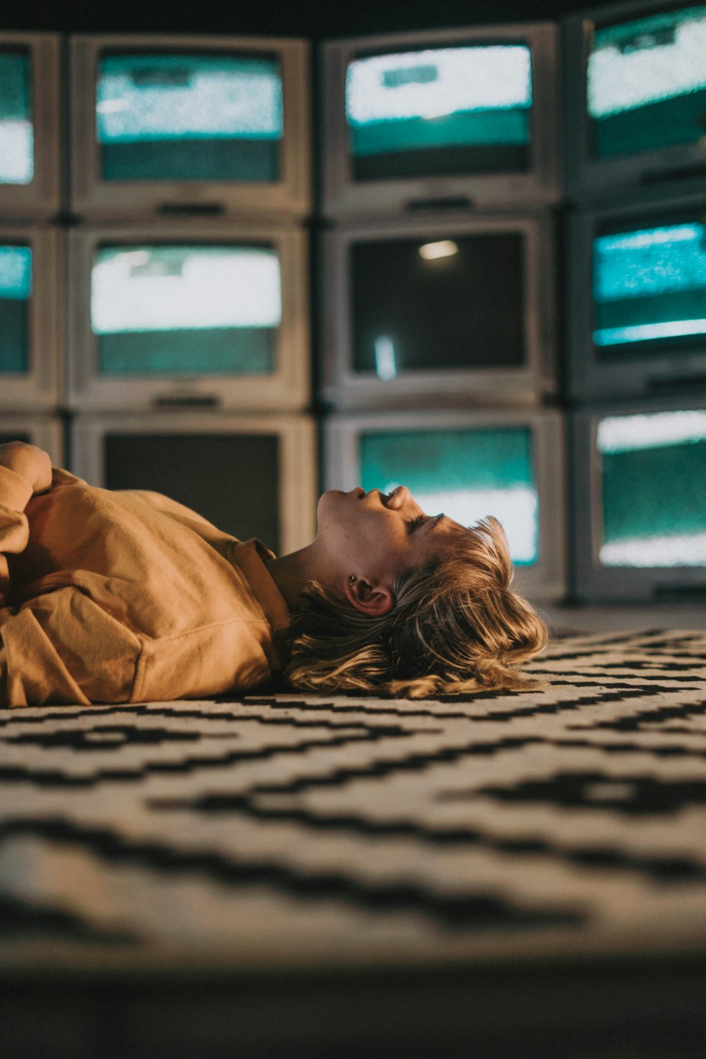 woman in brown shirt lying on black and white textile