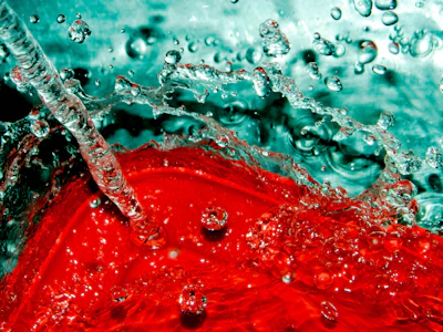Dynamic splash of electric teal liquid bursting from a Divorox can, illuminated by neon amber light.
