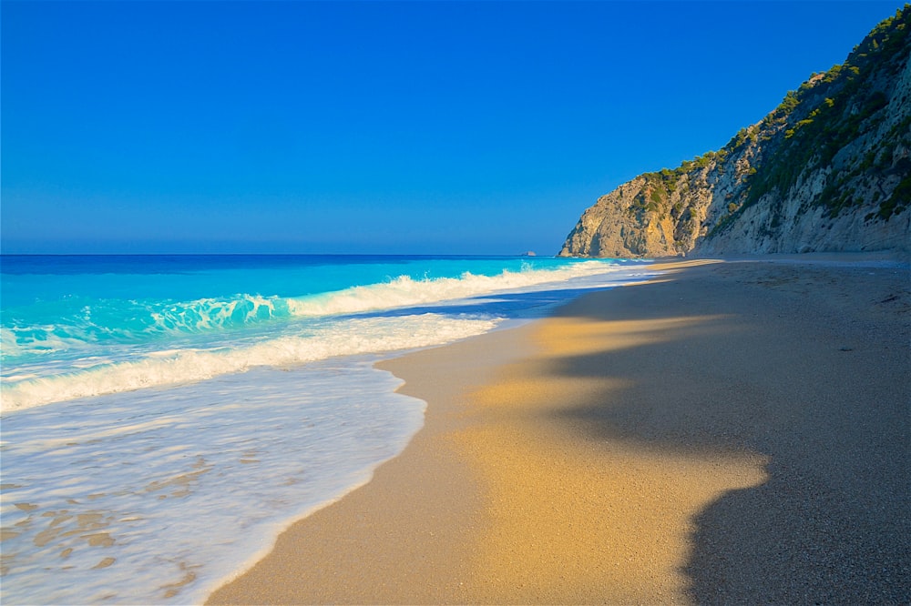 낮에는 푸른 바닷물이 있는 갈색 모래 해변