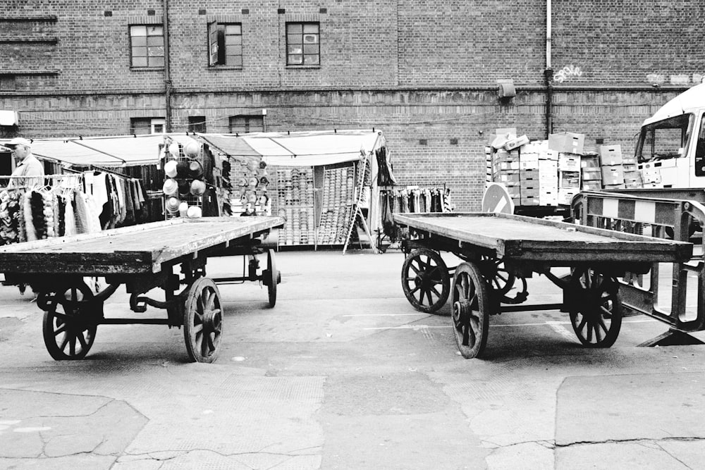 grayscale photo of man in black jacket sitting on black wooden cart