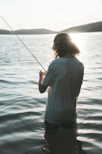 A fisherman casting a line into a serene Brazilian river at sunset.