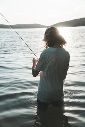 A fisherman casting a line into a serene Brazilian river at sunset.