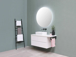 A sleek modern matte black vanity lamp shining brightly on a minimalist bathroom counter.