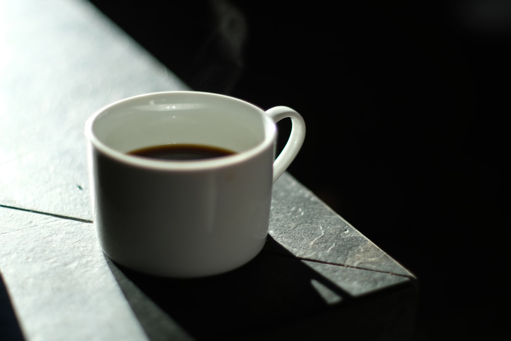 white ceramic mug on black wooden table