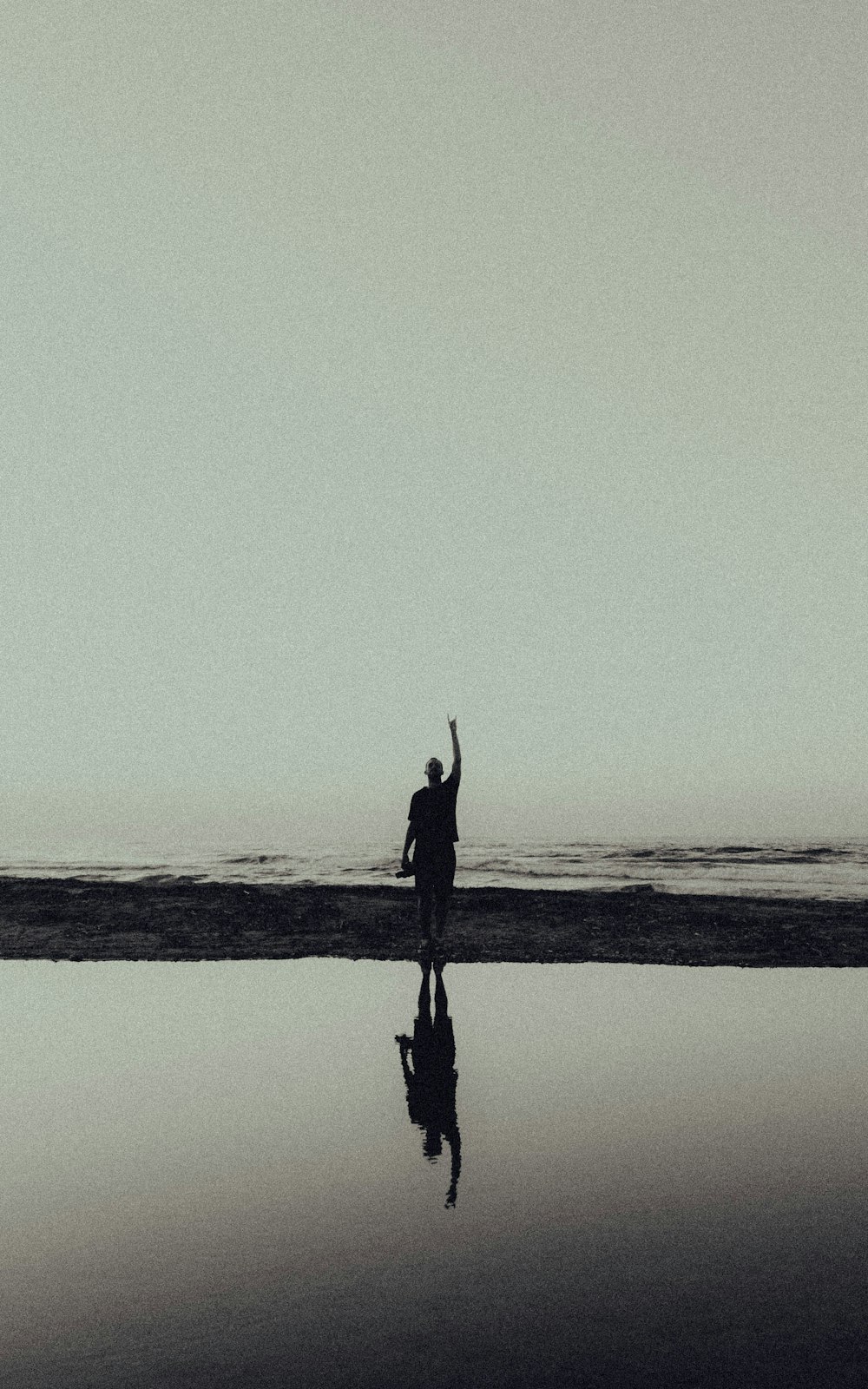 silhouette of man standing on seashore during daytime