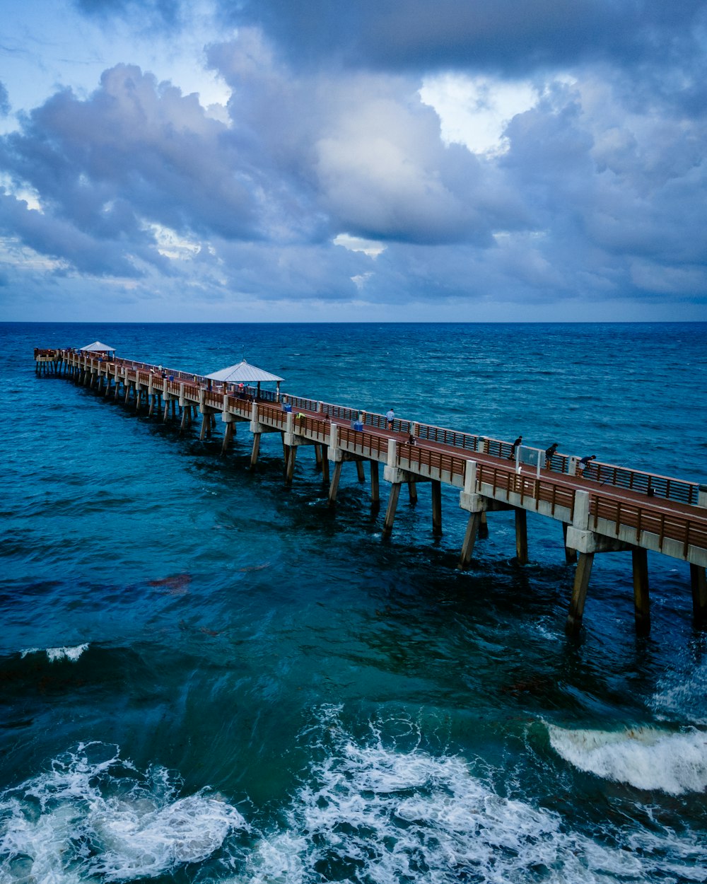 brown wooden dock on blue sea under blue and white cloudy sky during daytime