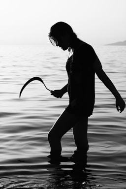 fine art photography,how to photograph fine art portrait; woman in black long sleeve shirt and pants holding rope on water