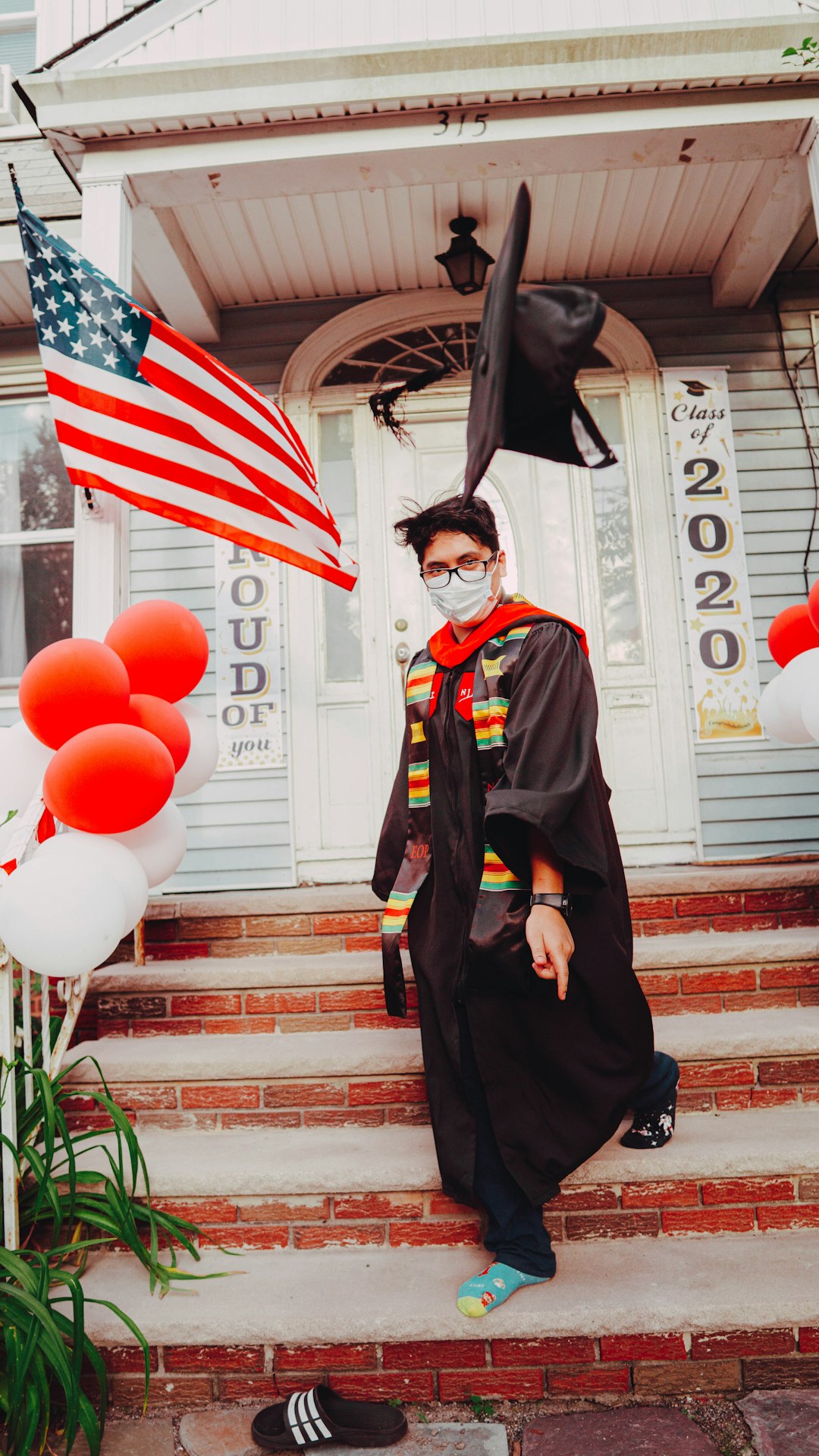 woman in black academic dress standing beside red and white balloons