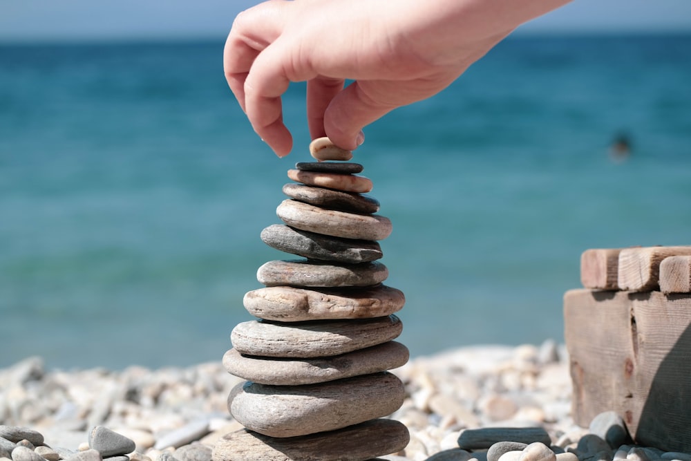 person holding stack of stones