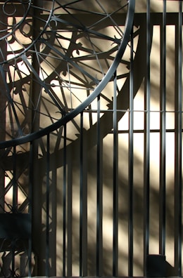Close-up of a metal geometric hanging ornament casting shadows on a white wall.