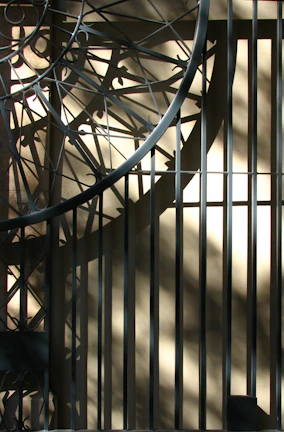 An intricate iron wall sculpture casting interesting shadows on a white wall.