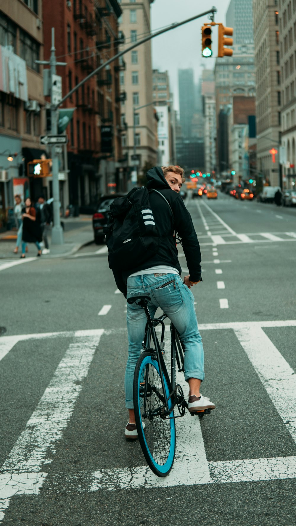 man in black jacket and blue denim jeans riding bicycle on road during  daytime photo – Free Grey Image on Unsplash