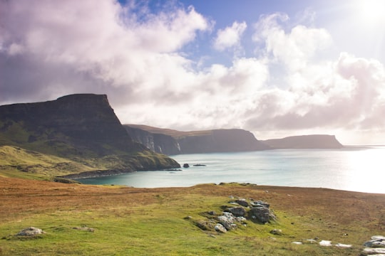 green grass field near body of water under white clouds during daytime in Neist Point Lighthouse United Kingdom