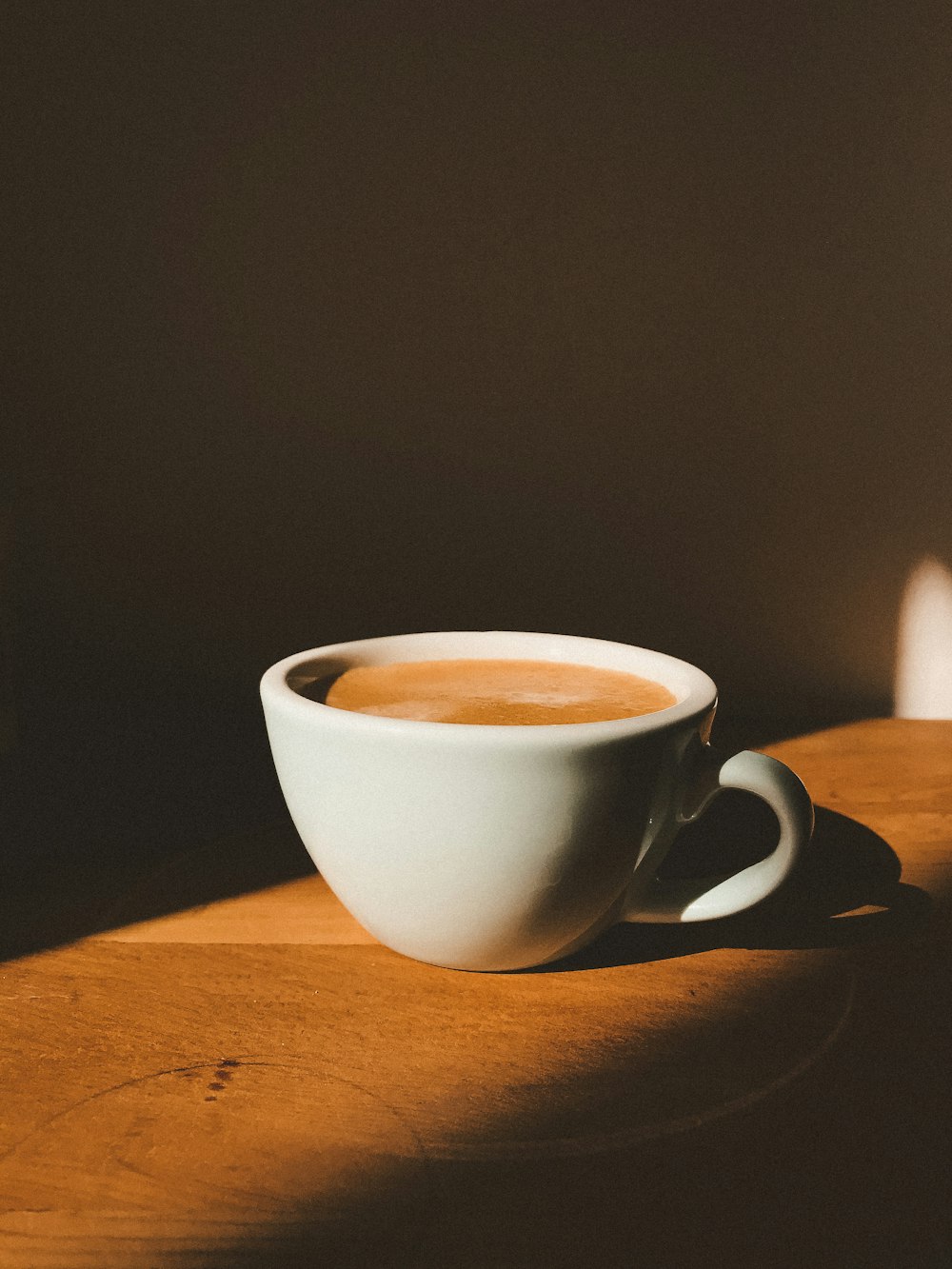 taza de cerámica blanca sobre mesa de madera marrón