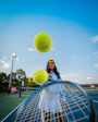 woman in black jacket and black pants holding tennis racket under blue sky during daytime