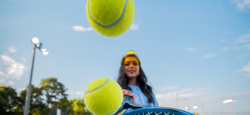 woman in black jacket and black pants holding tennis racket under blue sky during daytime