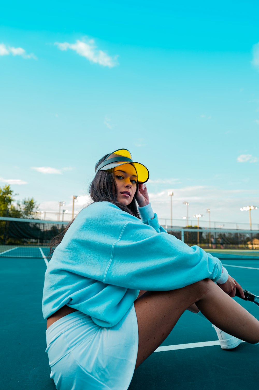 woman in teal hoodie and yellow cap sitting on boat during daytime