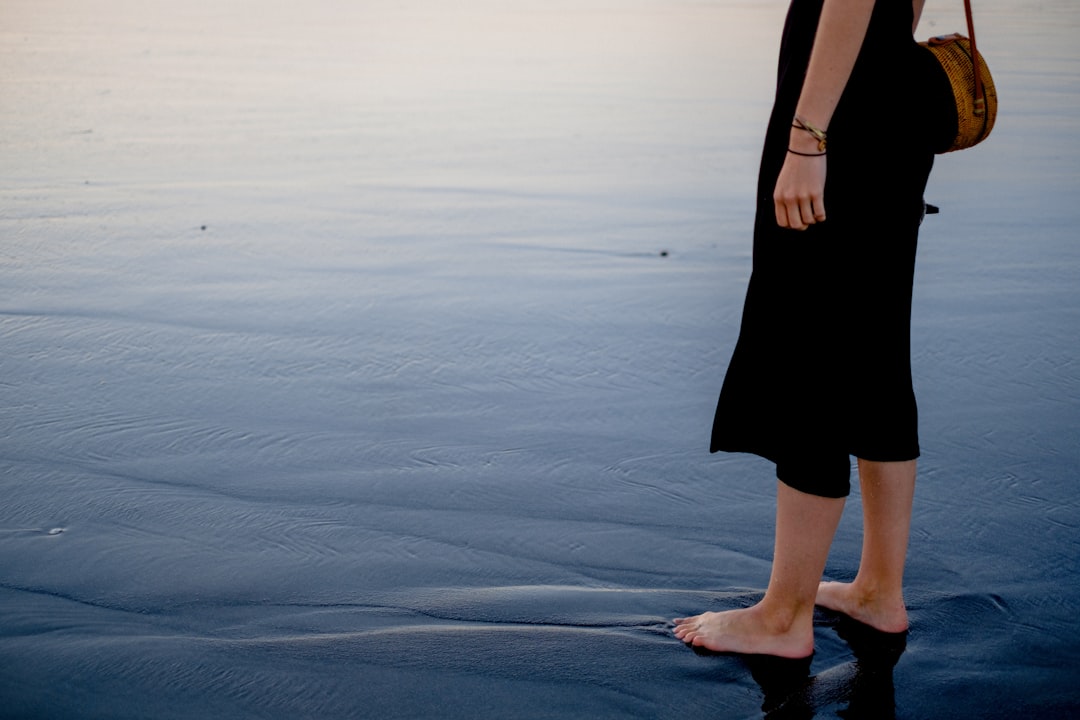 woman in black dress standing on sand during daytime