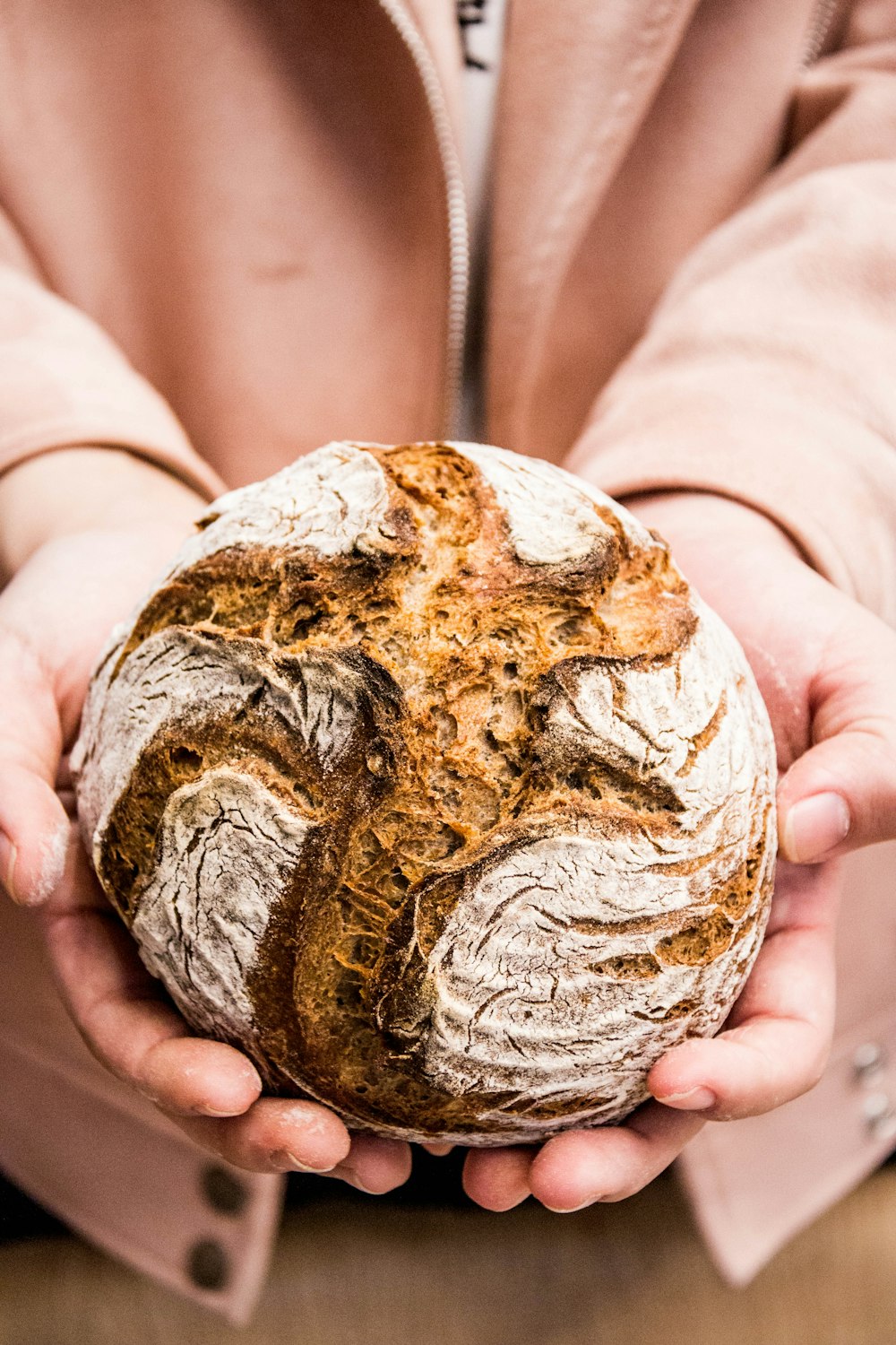 person holding brown and white round bread