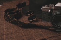 Cat-eye glasses elegantly placed beside a vintage camera on a rustic surface.