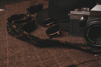 Cat-eye glasses elegantly placed beside a vintage camera on a rustic surface.