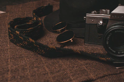 Flat lay of folded golden cotton t-shirts with a vintage camera and sunglasses.