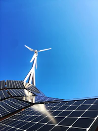 A modern green energy investment concept with wind turbines and solar panels under a clear blue sky.