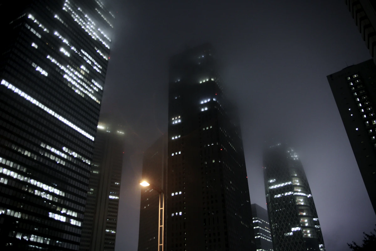 霧の中に高層ビルが立ち並ぶ都市の夜景