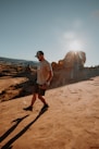 man in white shirt and black shorts standing on brown sand during daytime
