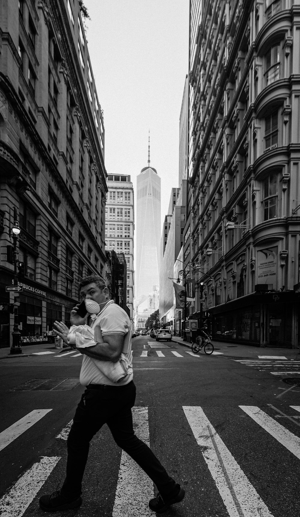 man in white long sleeve shirt and black pants sitting on sidewalk in grayscale photography