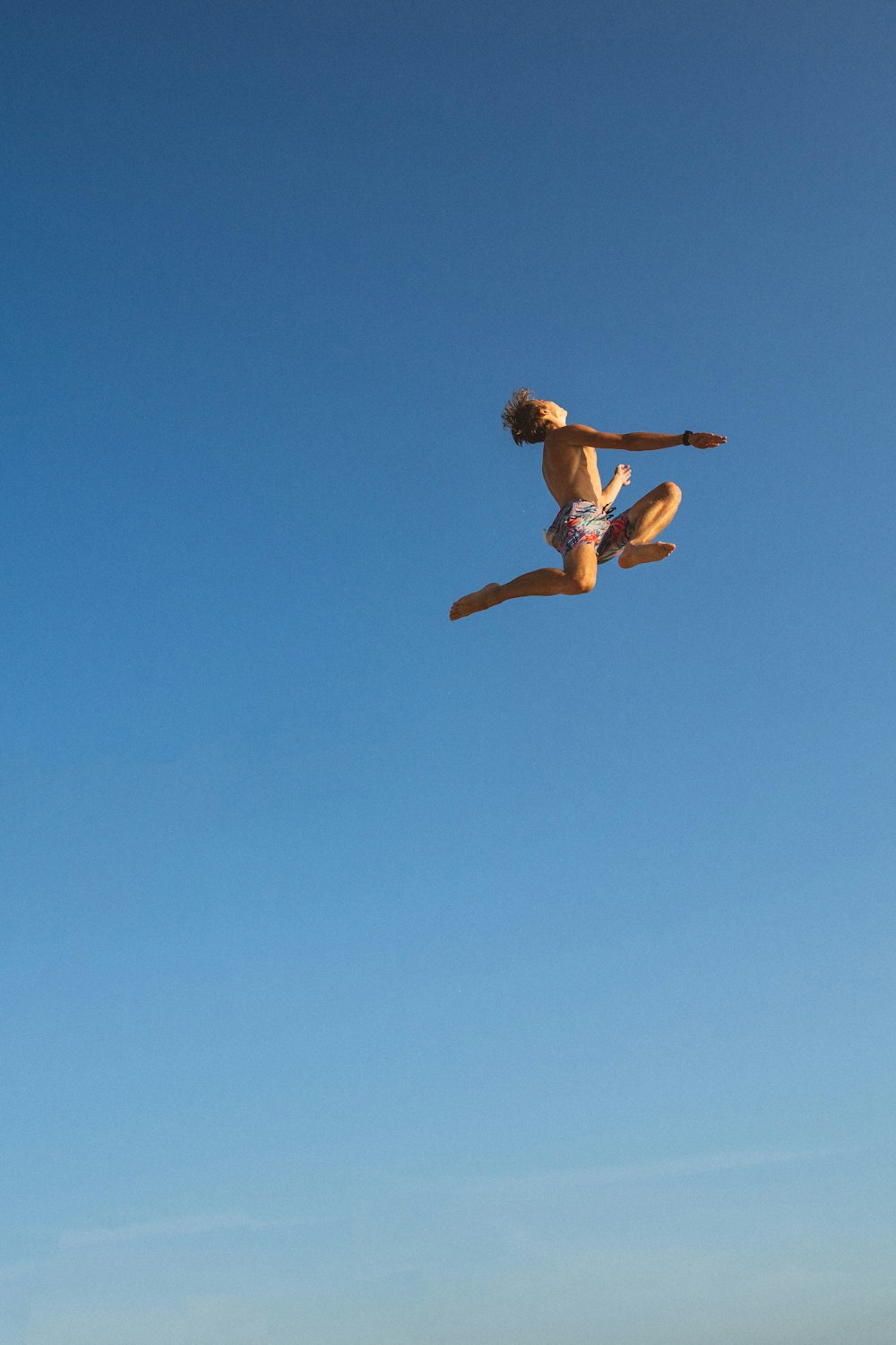 man in black shorts jumping under blue sky during daytime