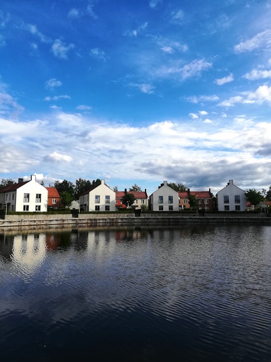 white and brown concrete house beside body of water under blue sky during daytime in Växjö Sweden