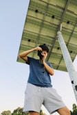 Technician holding a handheld device measuring solar panel output on a rooftop under clear skies