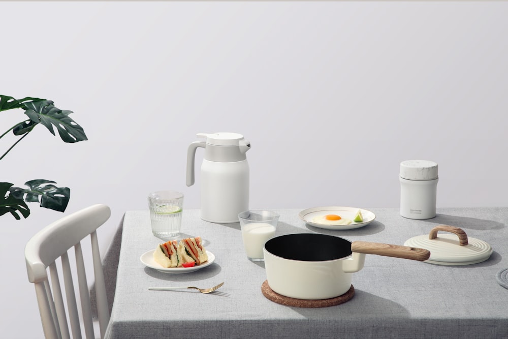 white and black ceramic mug on white ceramic plate beside white ceramic pitcher