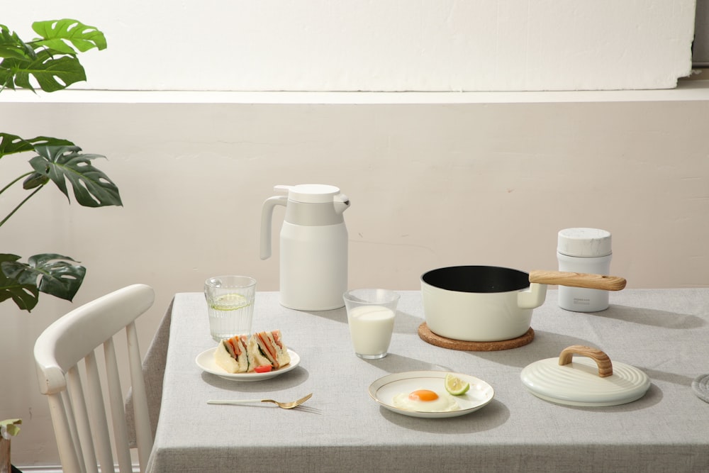 白いテーブルの上の白い陶磁器の茶碗の横の白い陶磁器の版の白い陶磁器の茶碗