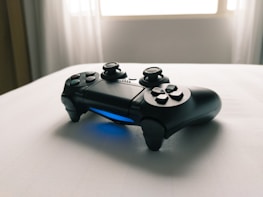 Close-up of a game controller resting near a mechanical keyboard on a minimalist desk, bathed in warm, natural light.