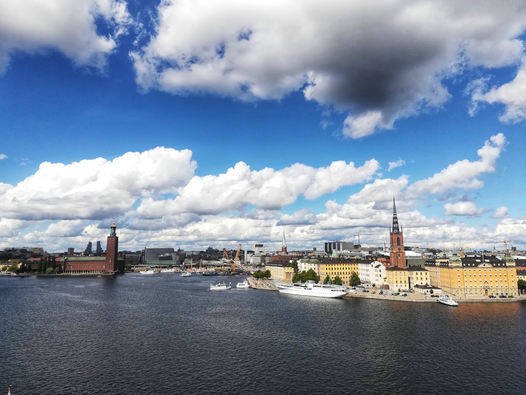 body of water near city buildings under blue and white sunny cloudy sky during daytime